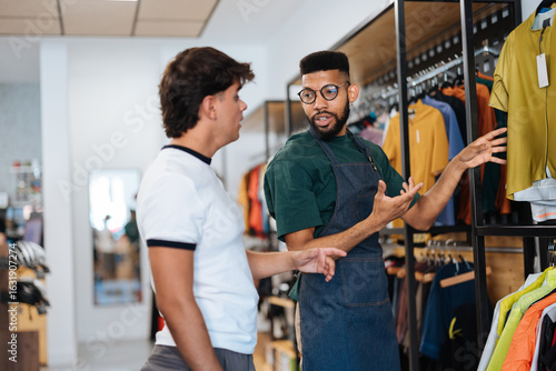 Cuadro en lienzo Shop assistant showing cycling apparel to customer in bike shop