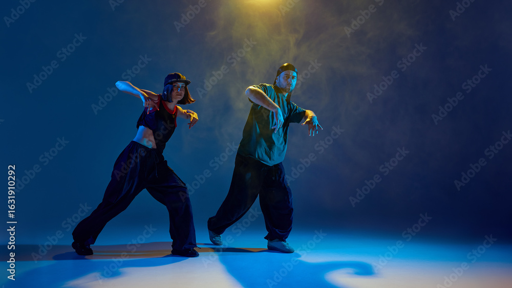 Dancers in low pose with theatrical lighting and intense emotional expression. Concept of dance events, creative performance, branding visuals, emotional youth storytelling. Dancers in low pose with theatrical lighting and intense emotional expression. Concept of dance events, creative performance, branding visuals, emotional youth storytelling.