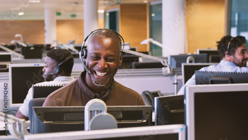 Fotografija Mature Businessman Wearing Telephone Headset Working In Customer Services Depart