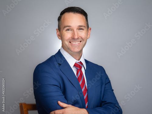 Portrait of white male professional in a blue suit and red tie. 