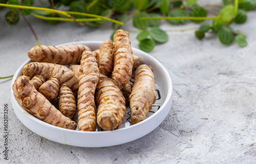 Fresh Organic Turmeric Roots in a White Ceramic Bowl
