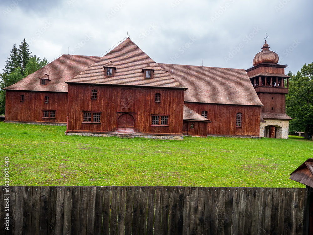 Fototapeta premium Wooden articular church in Svätý Kríž, Slovakia, surrounded by trees and fence. Historic Lutheran church built from timber in traditional style.