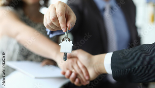 Celebrating the joyous moment of handing over house keys during a real estate transaction in a bright modern office setting