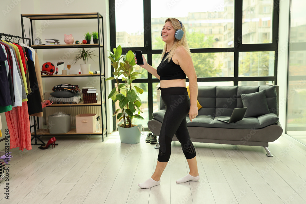 Fototapeta premium Joyful dance in a modern apartment during a sunny day with headphones on, embracing the rhythm and energy of life