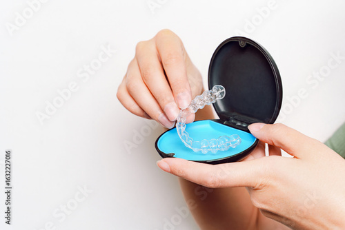 Person Holding Clear Aligner Over Open Case