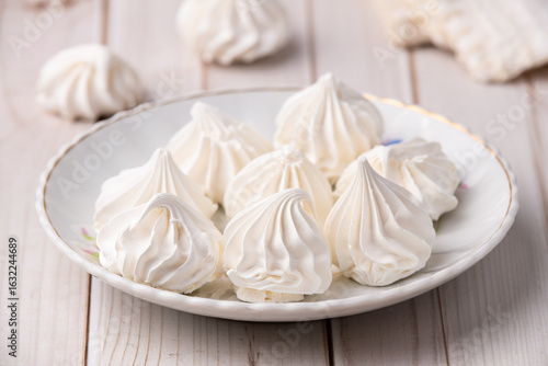Fresh homemade meringue cookies over wooden table