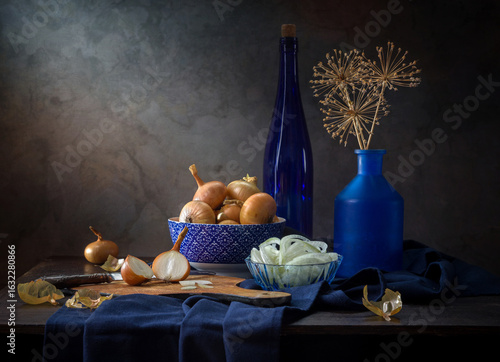 Contemporary still life with onions and blue dishes on a dark background