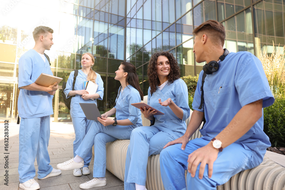 Fototapeta premium Group of medical students in uniforms studying together near building outdoors