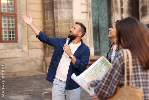 Guide with microphone and tourists on city street during excursion