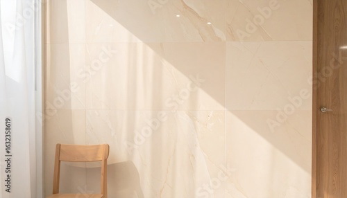 Minimalist Beige Marble Wall with Wooden Chair Illuminated by Sunlight and Partial Curtain