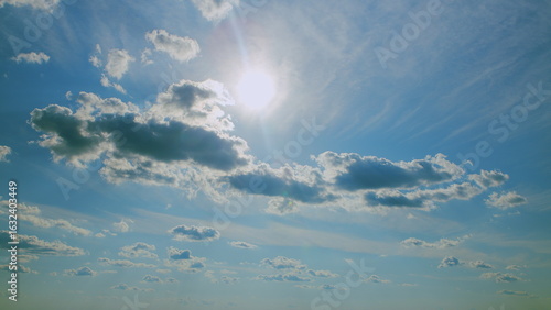 Fototapeta Naklejka Na Ścianę i Meble -  A beautiful scenic sky adorned with fluffy clouds and warm, bright sunlight streaming through