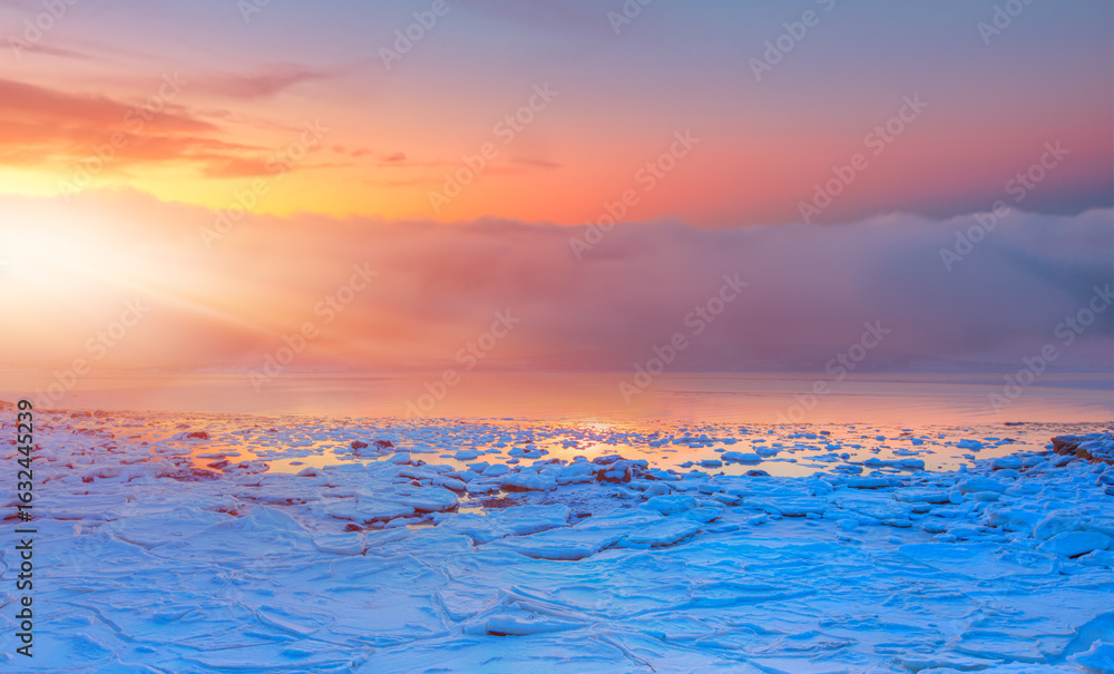 Naklejka premium Panoramic view at fjord with coast of the Norwegian sea in the background snowy mountains at sunset - Snowy winter in the Arctic Circle - Tromso, Norway