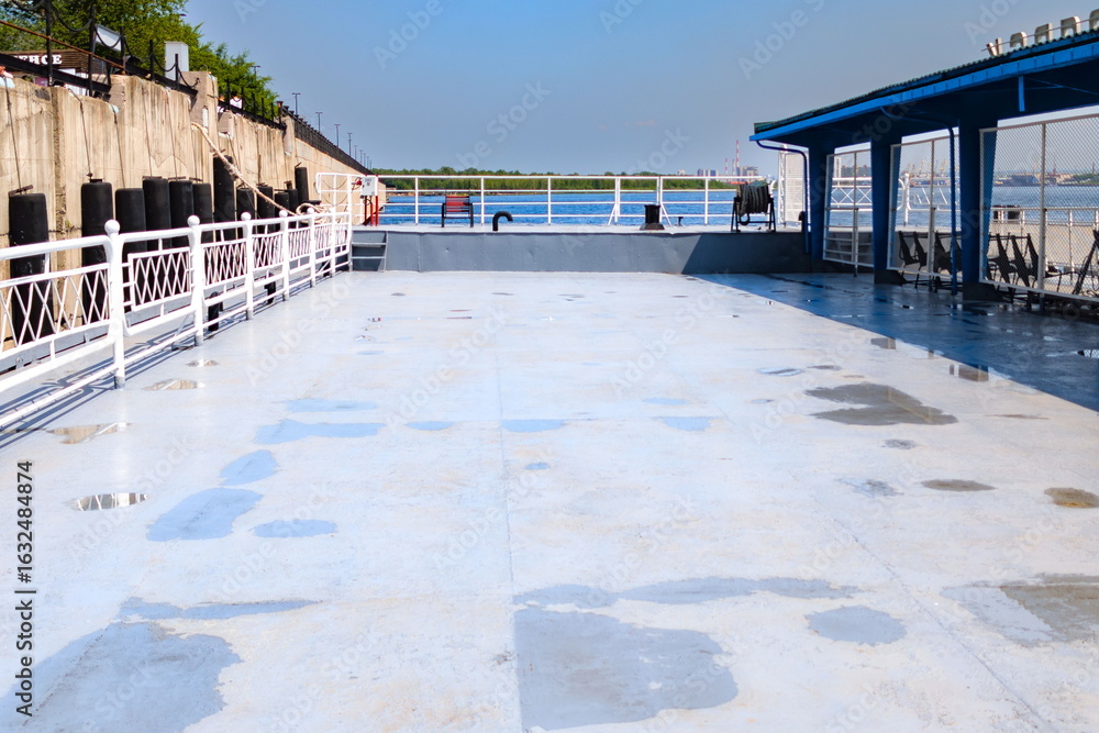 Φωτογραφία Deck of a riverboat docked at the waterfront, showcasing blue skies and clean su