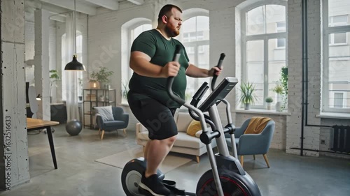 very fat   man exercising on elliptical trainer at home in modern living room
