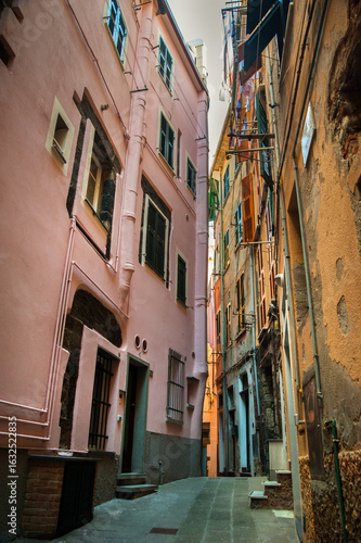 Narrow street between houses with colorful facades, windows with shutters, li...