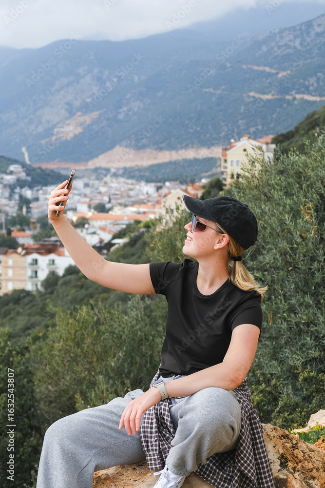 Naklejka premium Solo female traveler enjoys scenic coastal view during eco-conscious hiking retreat. Digital nomad lifestyle, nature detox, and mindful escape for remote work and inner balance.