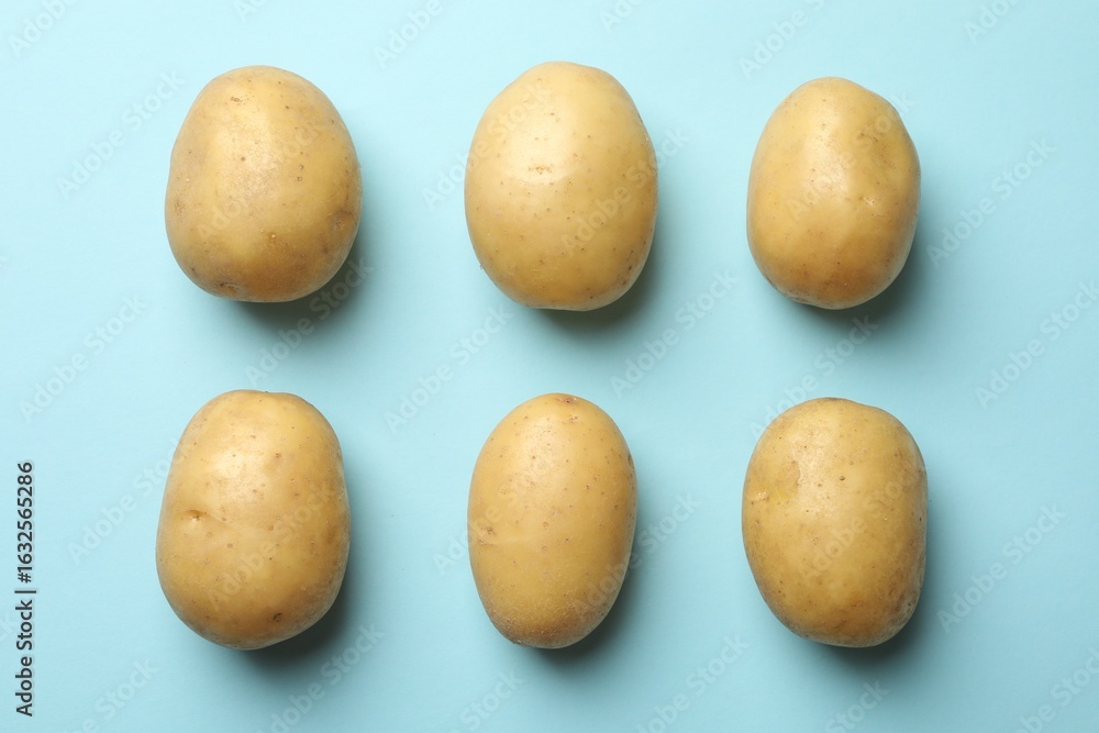 Fototapeta premium Fresh raw potatoes on light blue background, top view