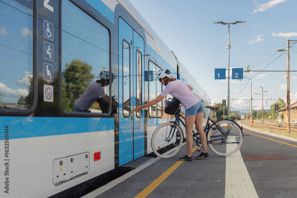 Fototapeta premium A cyclist boards a train with their bicycle at a station, showcasing convenient transportation options.