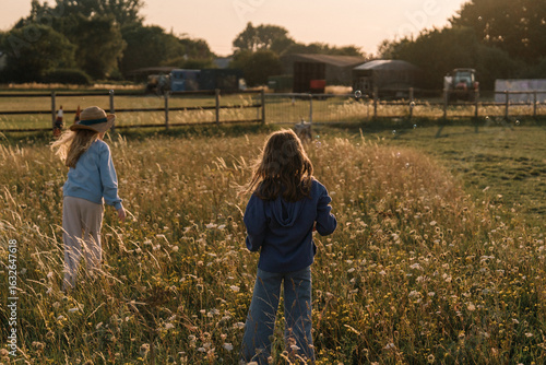 two girls are in a wheat field at sunset