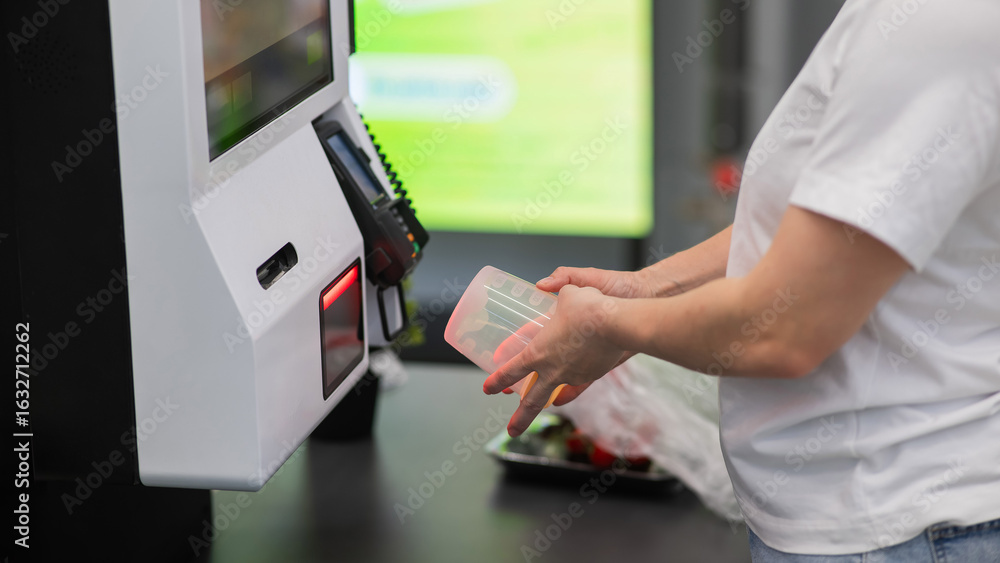 Obraz premium A woman scans items at a self-checkout. 