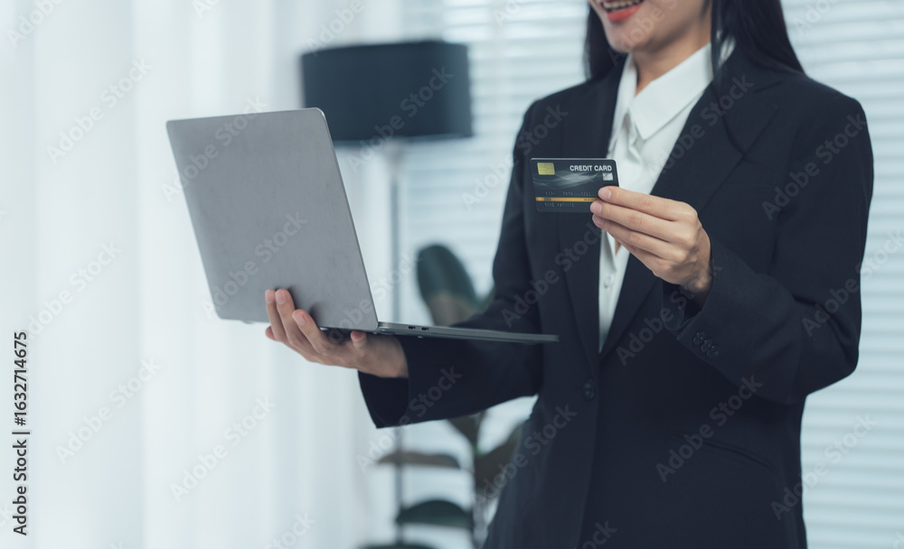 Online Payment: A professional in a black blazer, gracefully holding a credit card and laptop, embodying the ease and security of digital transactions in a modern setting. Online Payment: A professional in a black blazer, gracefully holding a credit card and laptop, embodying the ease and security of digital transactions in a modern setting.