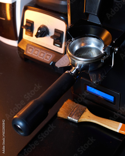 Close-up of an empty portafilter positioned under a professional espresso grinder, ready to receive freshly ground coffee