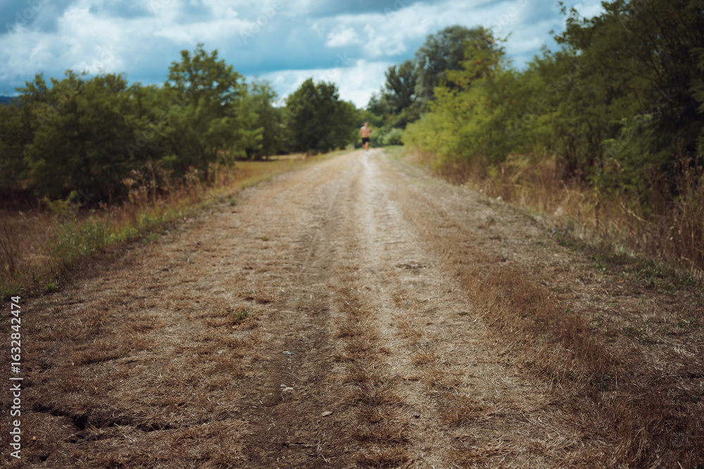 Fototapeta premium Rural footpath, in the distance a man is running