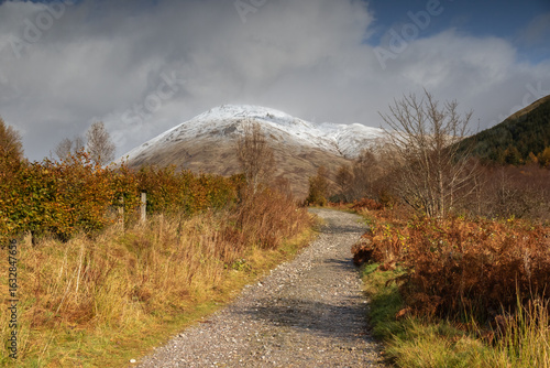 A path leading towards the hills dusted with the first snow on an autumn day. Next to Tyndrum, Scotland, UK. Old Military Road. West Highland Way