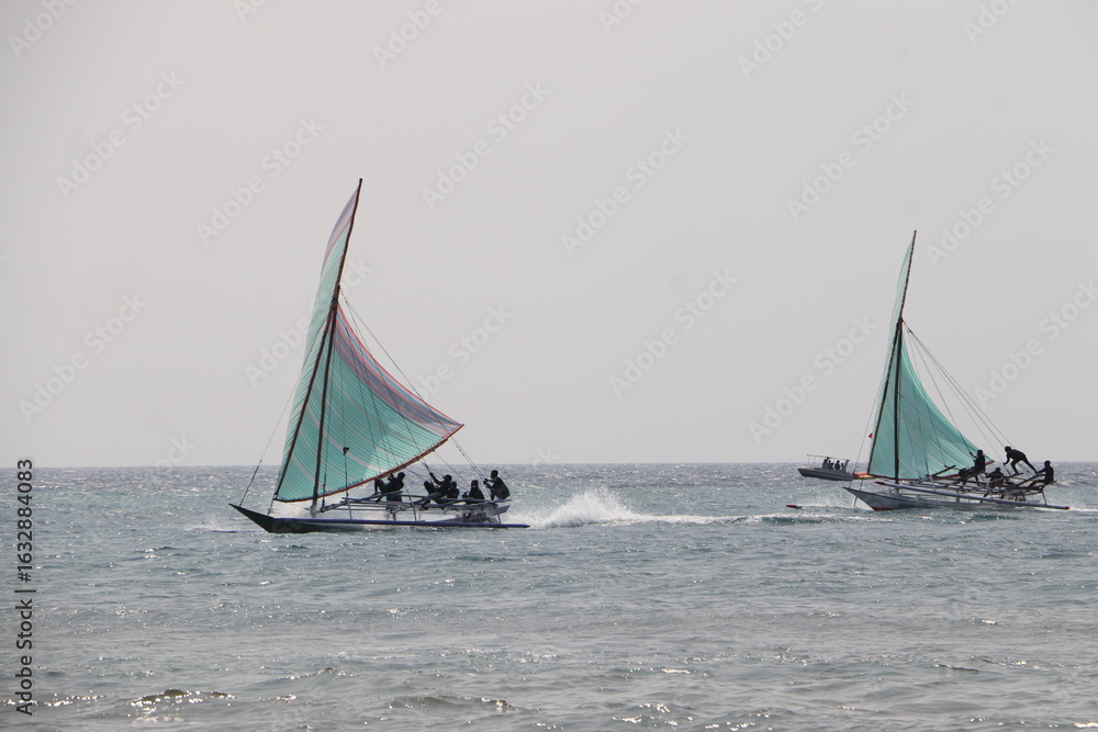 Fototapeta premium Bima, August 3, 2025 - Fishermen Competing in Traditional Sailing RegattaLocal Sailing Boat Festival with Colorful SailsColorful Wooden Sailboat Competition in Indonesia