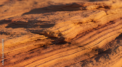 Close-up capturing the textural layers and warm hues of sandstone formations in a desert landscape.