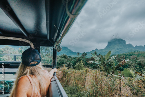 Tourist enjoying a scenic 4x4 safari adventure through lush jungle with a view of Mount Rotui, Moorea Island, French Polynesia.