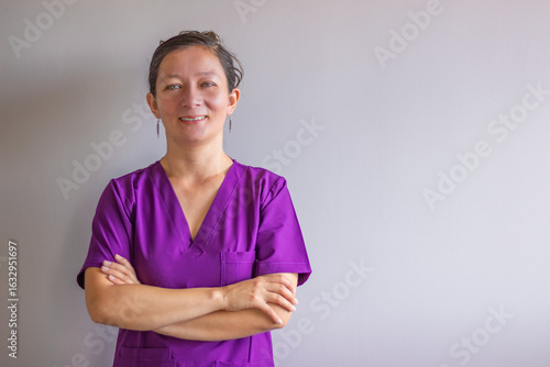 Confident nurse smiling with crossed arms in hospital