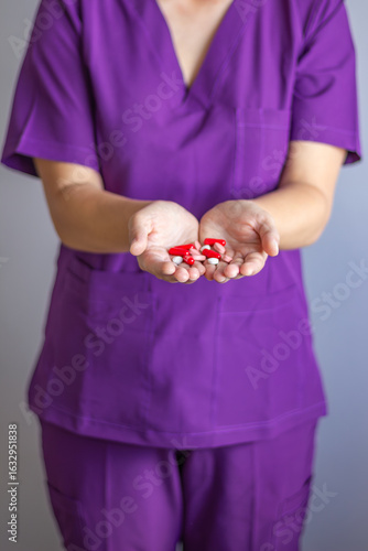 Doctor showing pills in open palms wearing purple scrubs