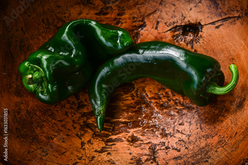 green whole fresh poblano chili peppers in vintage wooden bowl