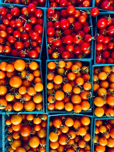 tiny hybrid tomatoes in square green plastic baskets on the tabletop at farmers market