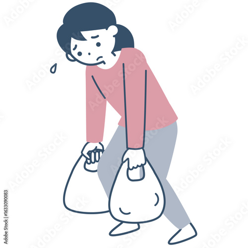 重い買い物袋を持って歩く若い女性