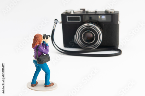 A toy photographer figurine photographing a vintage film camera