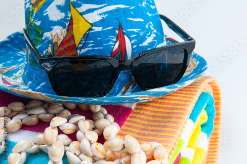 beach party hat, sunglasses and shell necklace on a striped towel