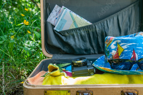 vintage suitcase for a vacation with a vintage film camera, a summer fedora and a rubber crocodile