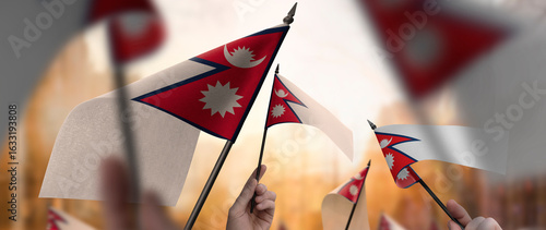 Nepal flags in their hands on a blurred urban background