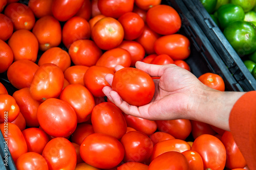 Fresh red tomatoes Hands picking one tomatoe in the supermarket