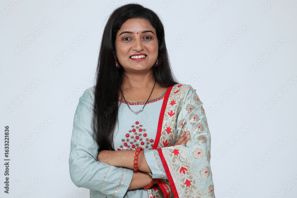 Traditional Indian woman in pleasant smile and crossed arms on grey studio background. happy face smiling with crossed arms looking at the camera. Confident and positive woman Traditional Indian woman in pleasant smile and crossed arms on grey studio background. happy face smiling with crossed arms looking at the camera. Confident and positive woman