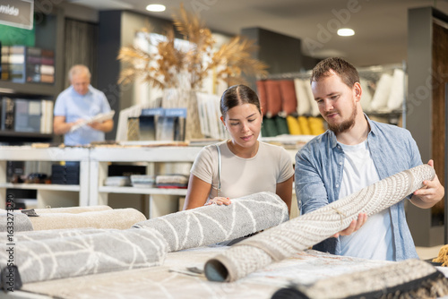 Fotografie While visiting store of building materials and related household goods, guy with wife choose carpet