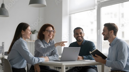 Four professionals engaged in a collaborative meeting around a table with a laptop and documents.