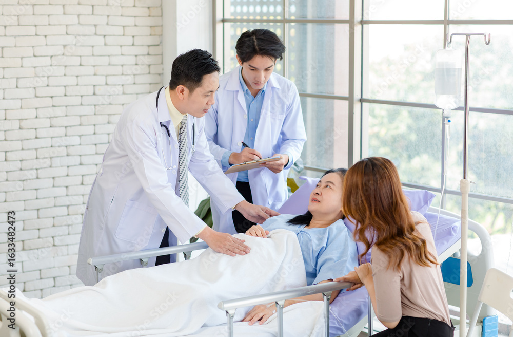 Asian man doctor and medical team visiting ward, consulting, talking to physician, senior woman patient lying on hospital bed room explaining medical treatment with family member showing care support. Asian man doctor and medical team visiting ward, consulting, talking to physician, senior woman patient lying on hospital bed room explaining medical treatment with family member showing care support.