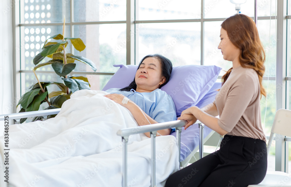 Obraz premium Asian lovely young daughter woman visiting elderly sick mother lying on hospital bed in private clinic room, Reassure woman assisting senior and parental care medicine family healthcare people concept