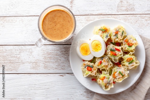 Wallpaper Mural An overhead shot of dumplings and hardboiled eggs on a plate with a beverage in a glass beside it all on a white wooden surface Torontodigital.ca