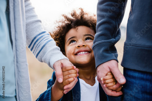 Wallpaper Mural Closeup of a happy mixedrace child looking up and holding hands with parents, symbolizing family love and connection Torontodigital.ca