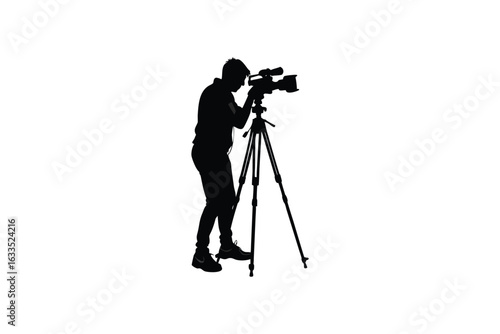 A lone cameraman in silhouette stands behind a professional video camera mounted on a tripod capturing a moment with focus and dedication silhouette