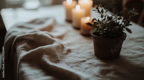 Soft linen tablecloth draped over a table, with candles and a small plant